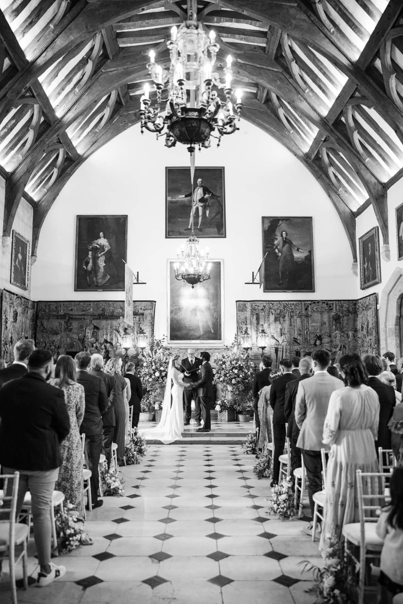Bride and Groom ceremony with paintings and chandelier in view at the Berkeley Castle Wedding Venue
