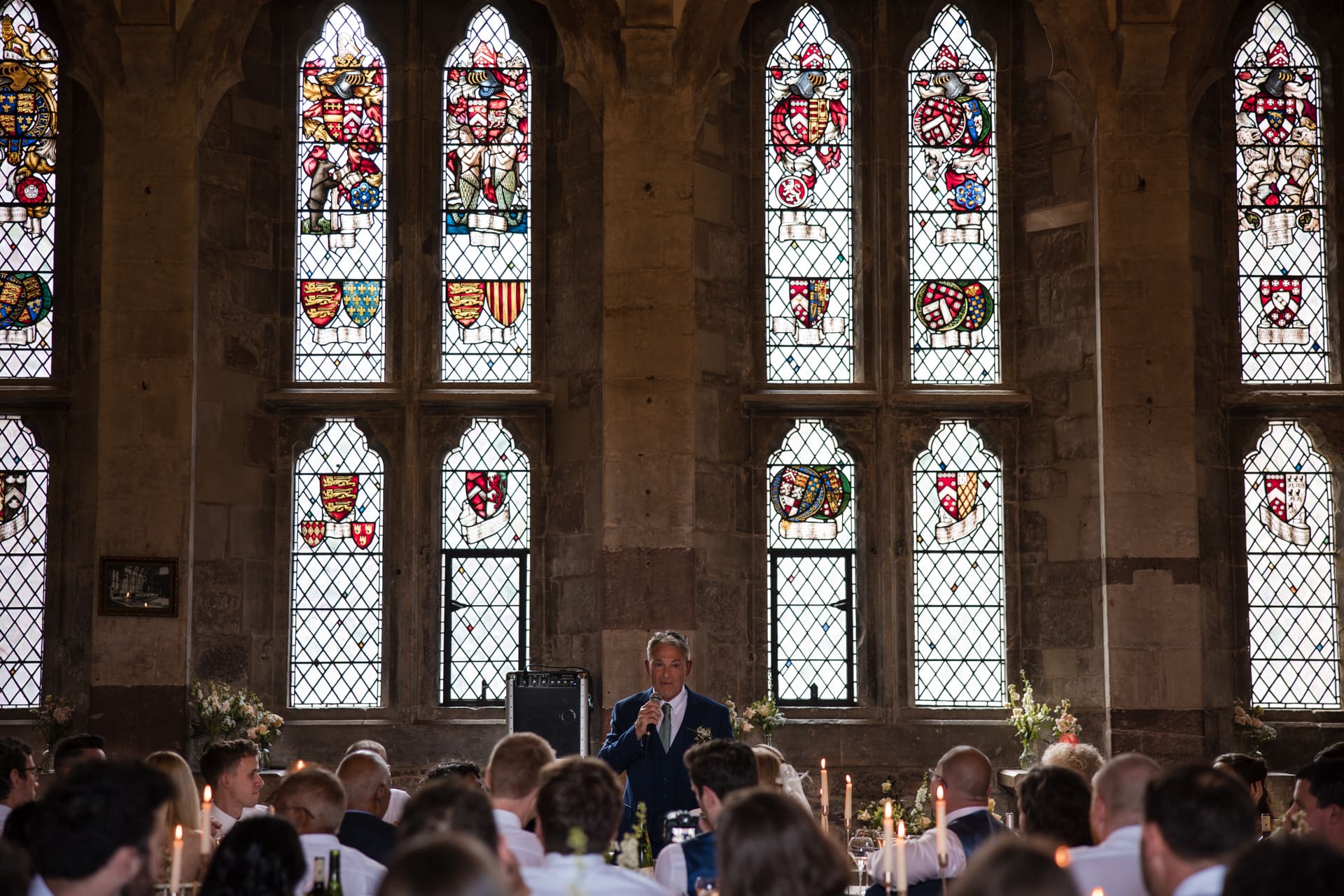 Father of the bride speech backlit by stained glass windows at Berkeley Castle Wedding Venue