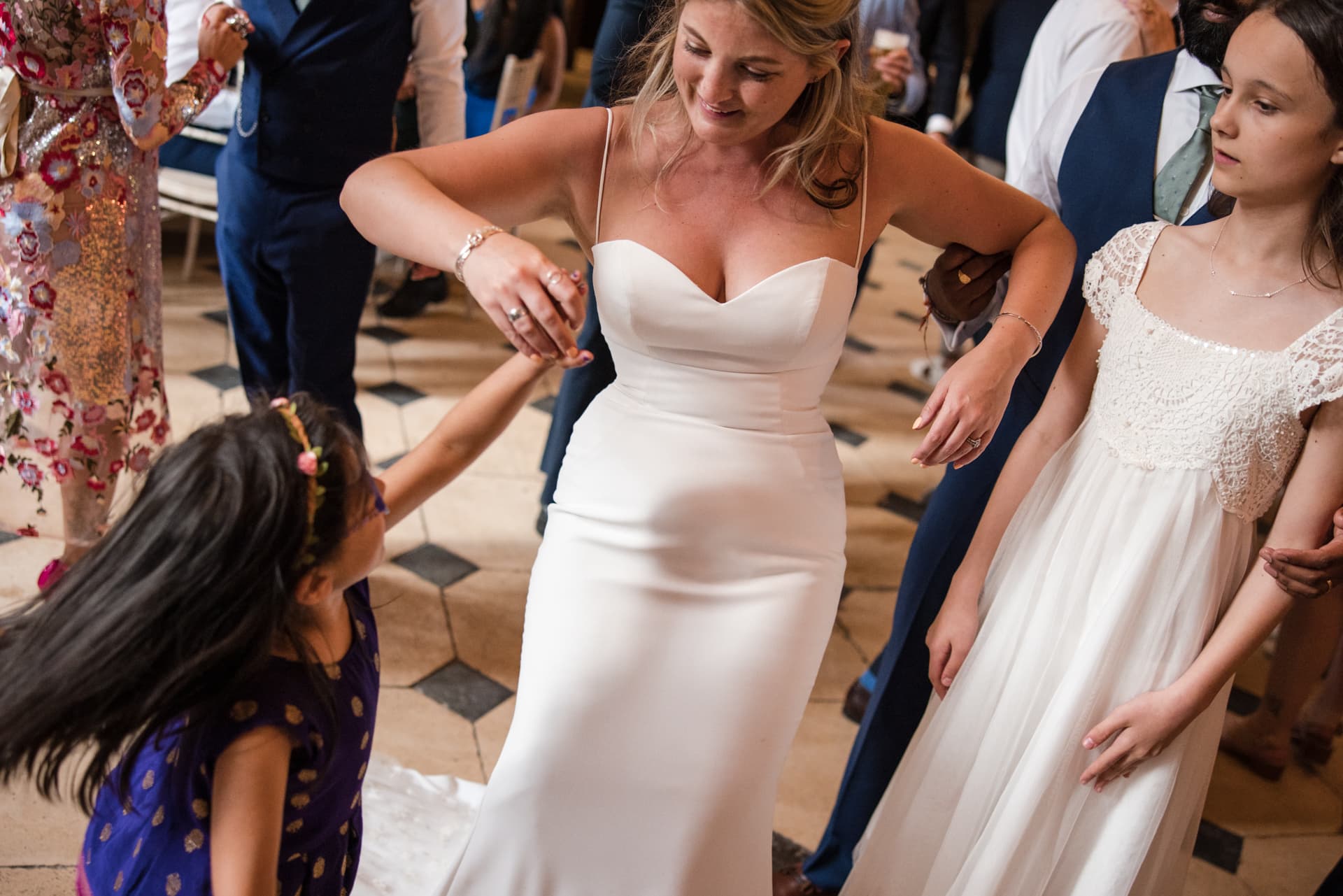 Bride dancing with young girl and bridesmaid