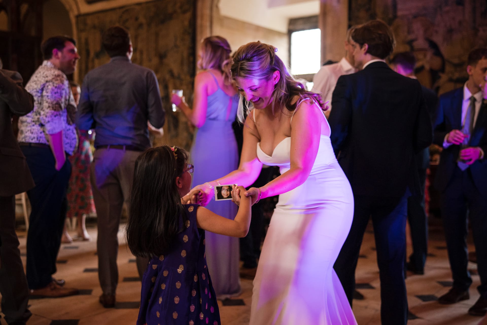 Bride dancing with young girl holding a photo of herself