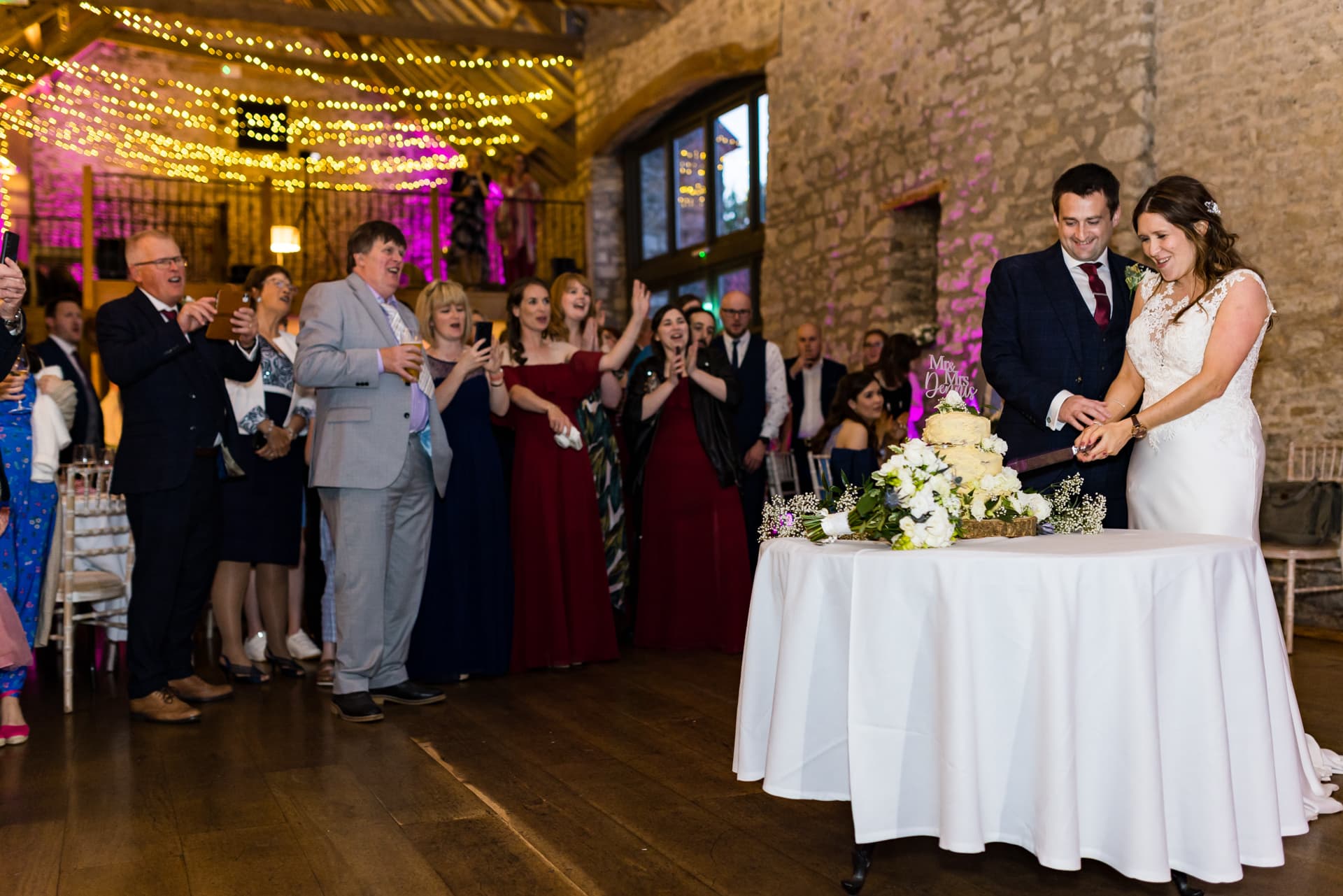 bride and groom cutting cake in barn