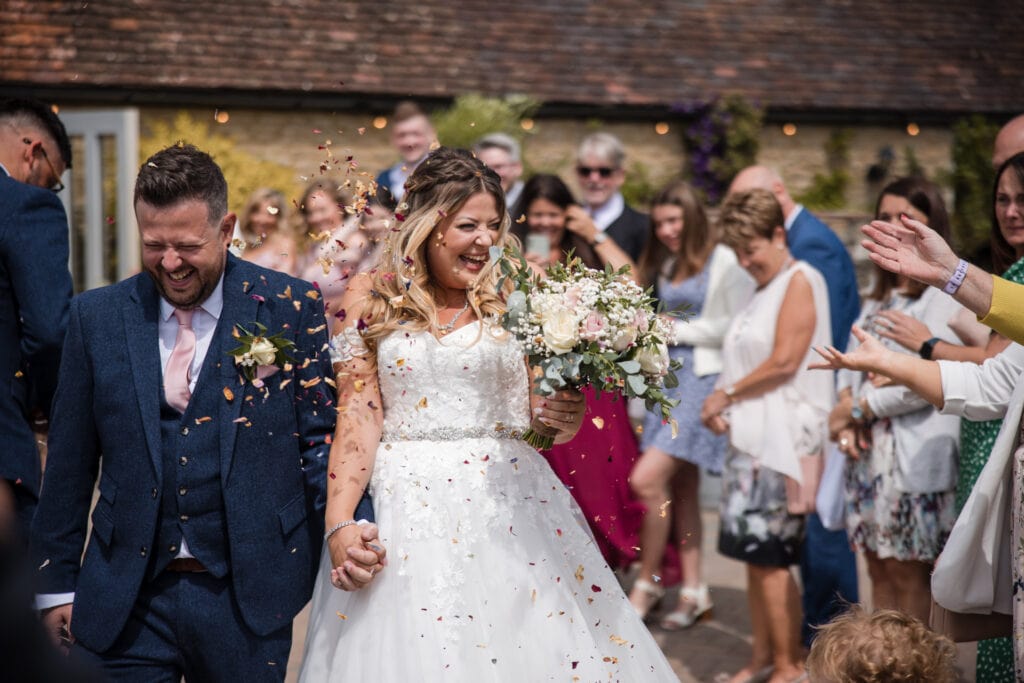 Bride and groom confetti walk laughing