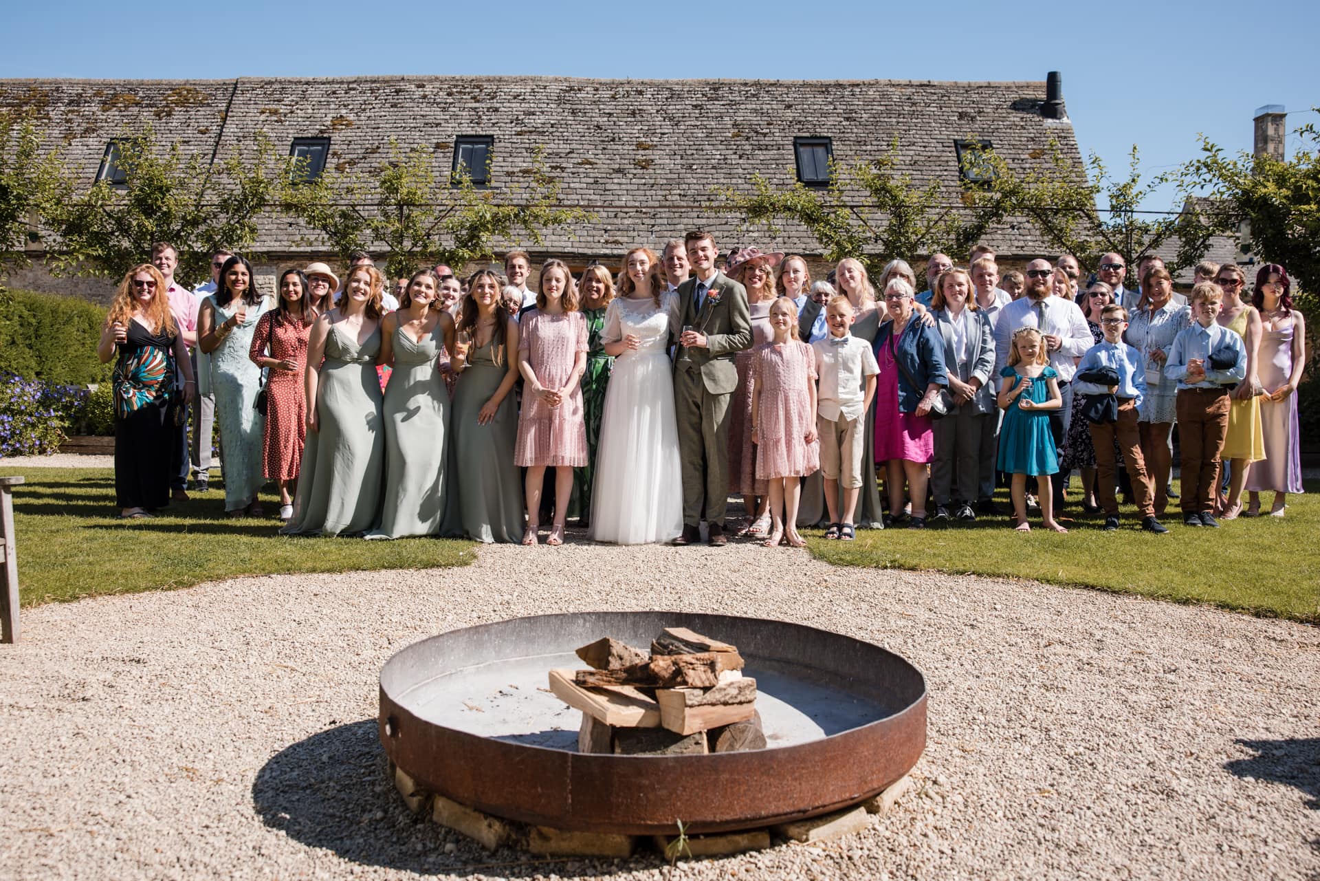 Wedding Part in front of fire pit of the Oxleaze Barn Wedding Venue
