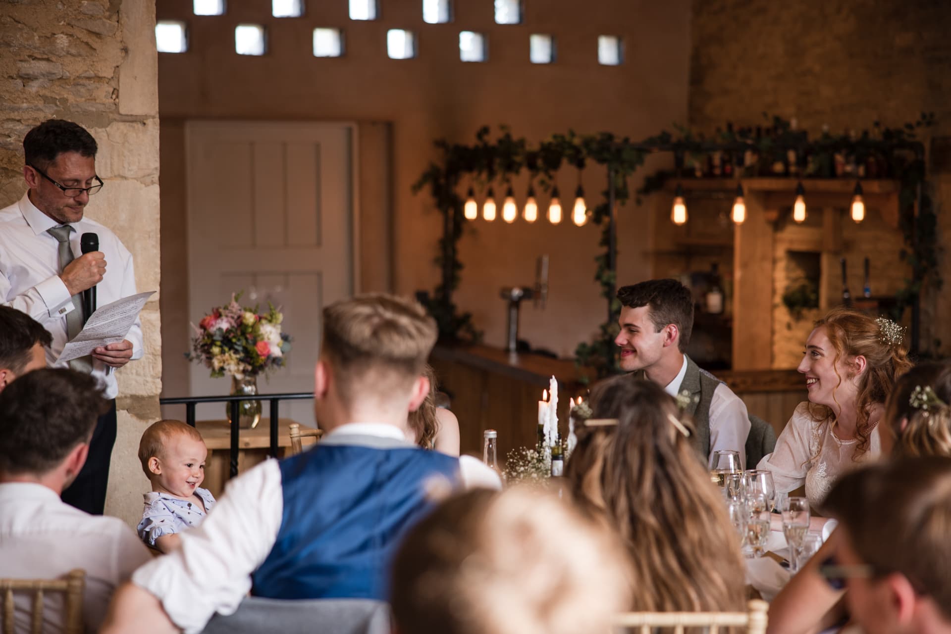 Father of the bride speech with the groom and bride onlooking at Oxleaze Barn Wedding Venue