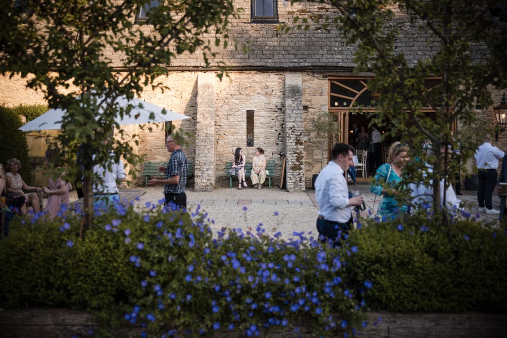 Two wedding guests sitting against stone building