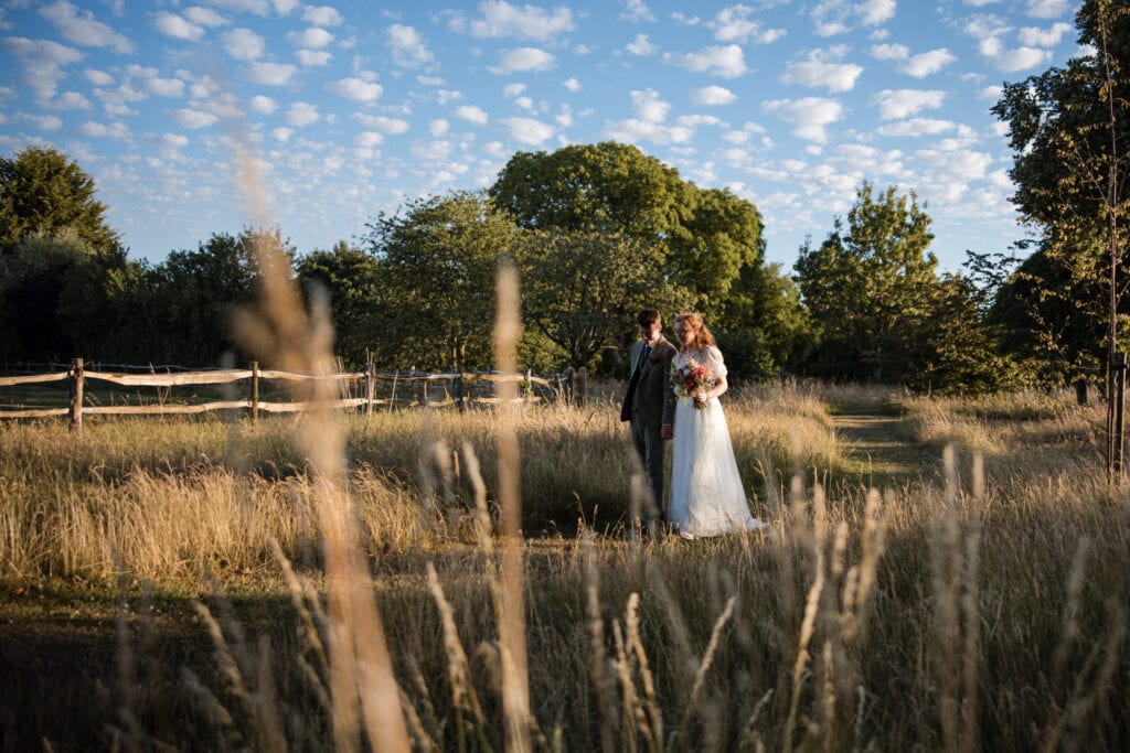 Bride and Groom walking in the fields next to Oxleaze Barn