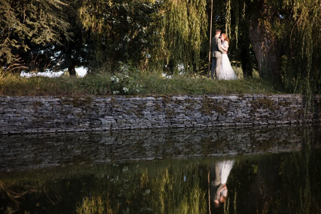 Bride and Groom photographed next to the Pond at Oxleaze Barn