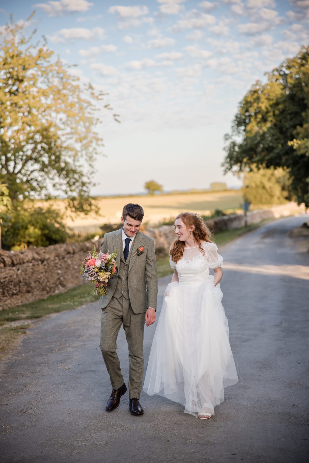Bride and Groom walking down the drive during sunset at Oxleaze Barn