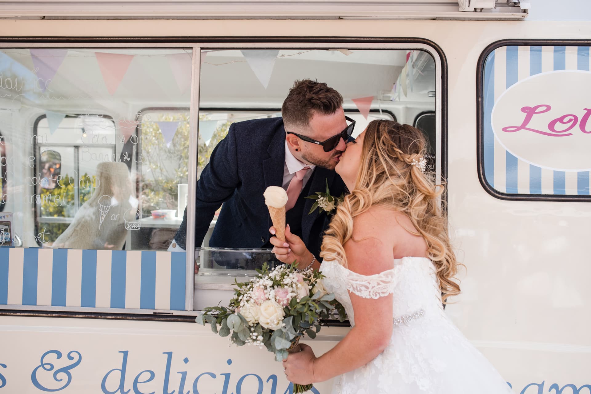 Bride and Groom kiss at the ice cream van in the Courtyard of Stratton Court Barn Wedding Venue