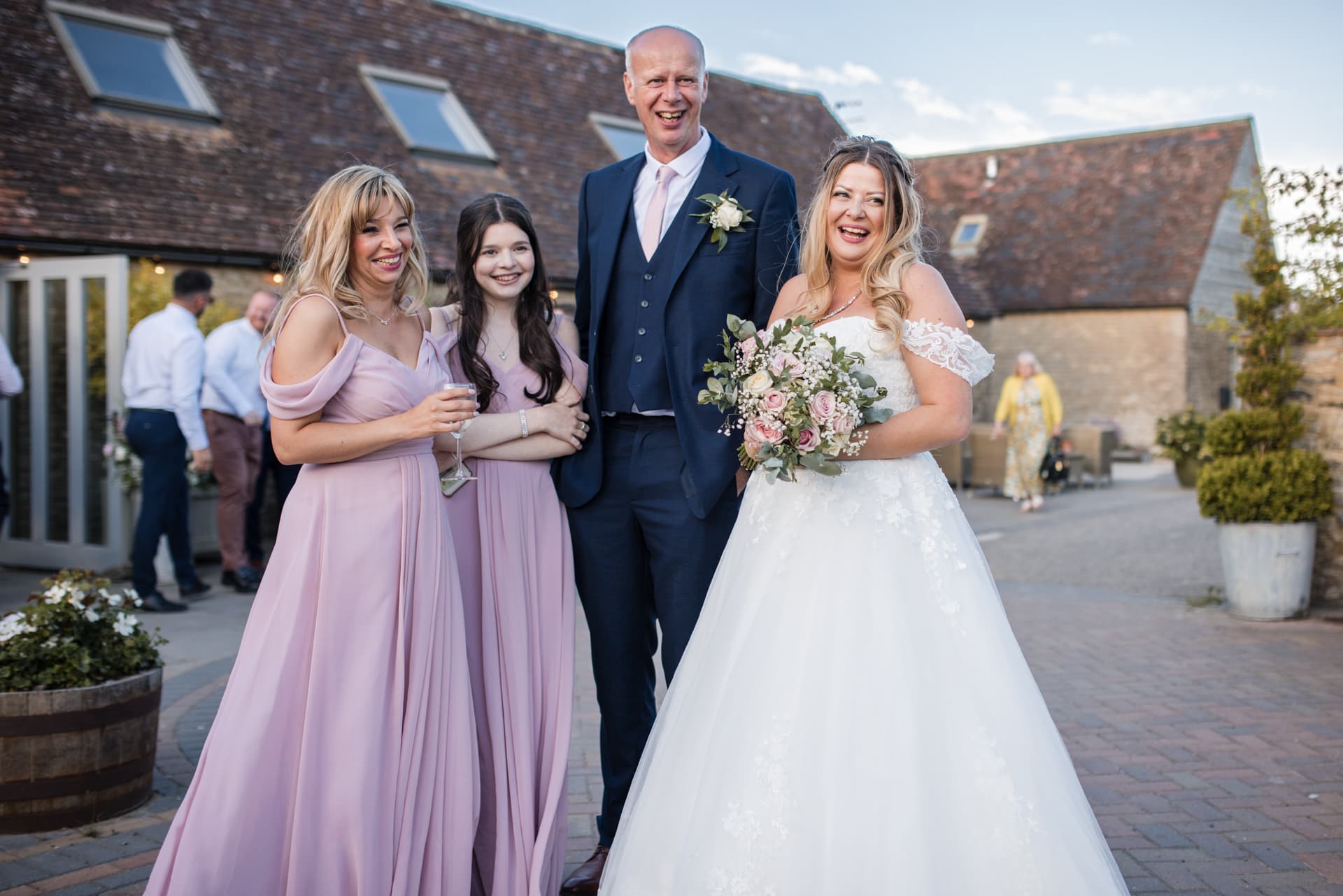 Wedding Party looking happy for camera in the courtyard of Stratton Court Barn Wedding Venue