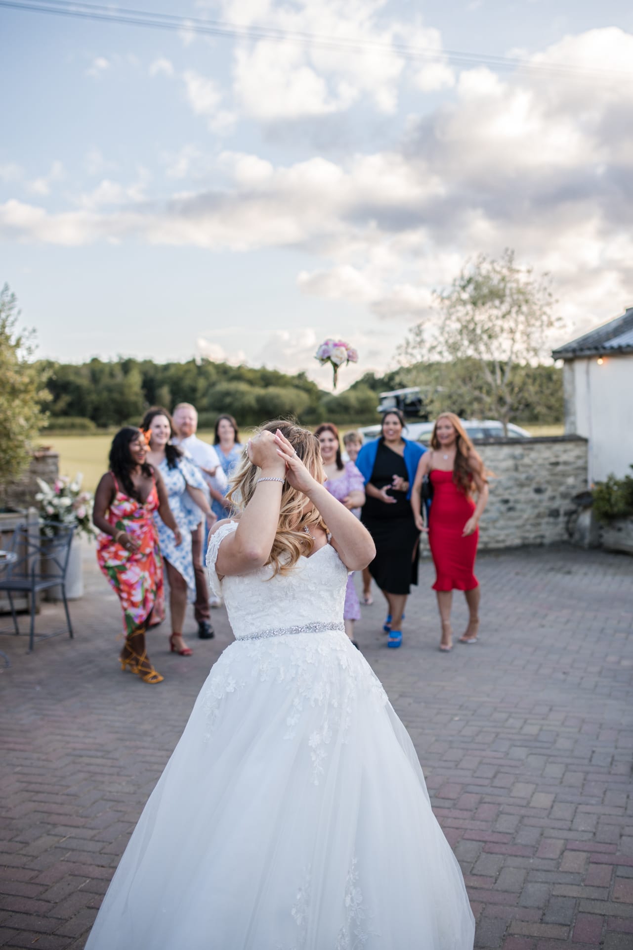 Bride throwing wedding bouquet to girls behind her