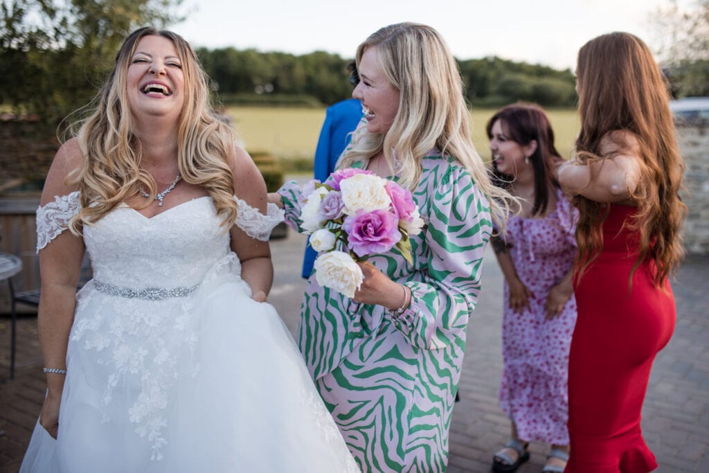 Birde and guest laughing after catching wedding bouquet