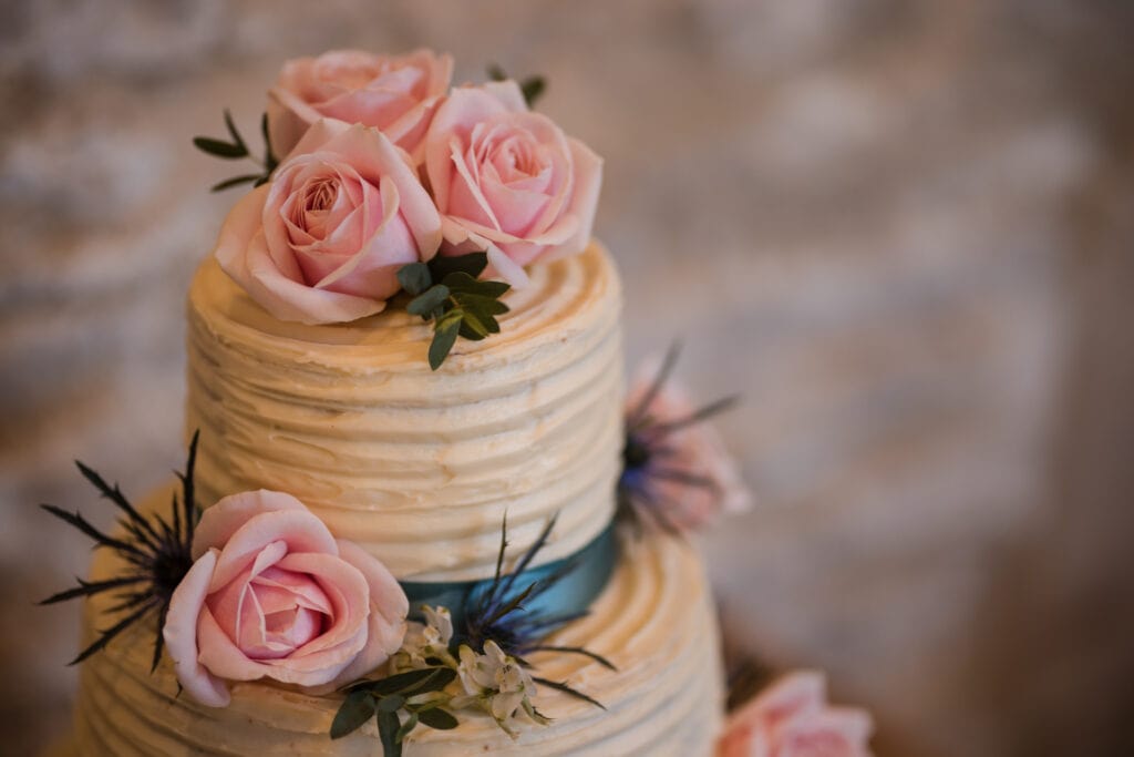 The top tier of wedding cake with pink roses on top