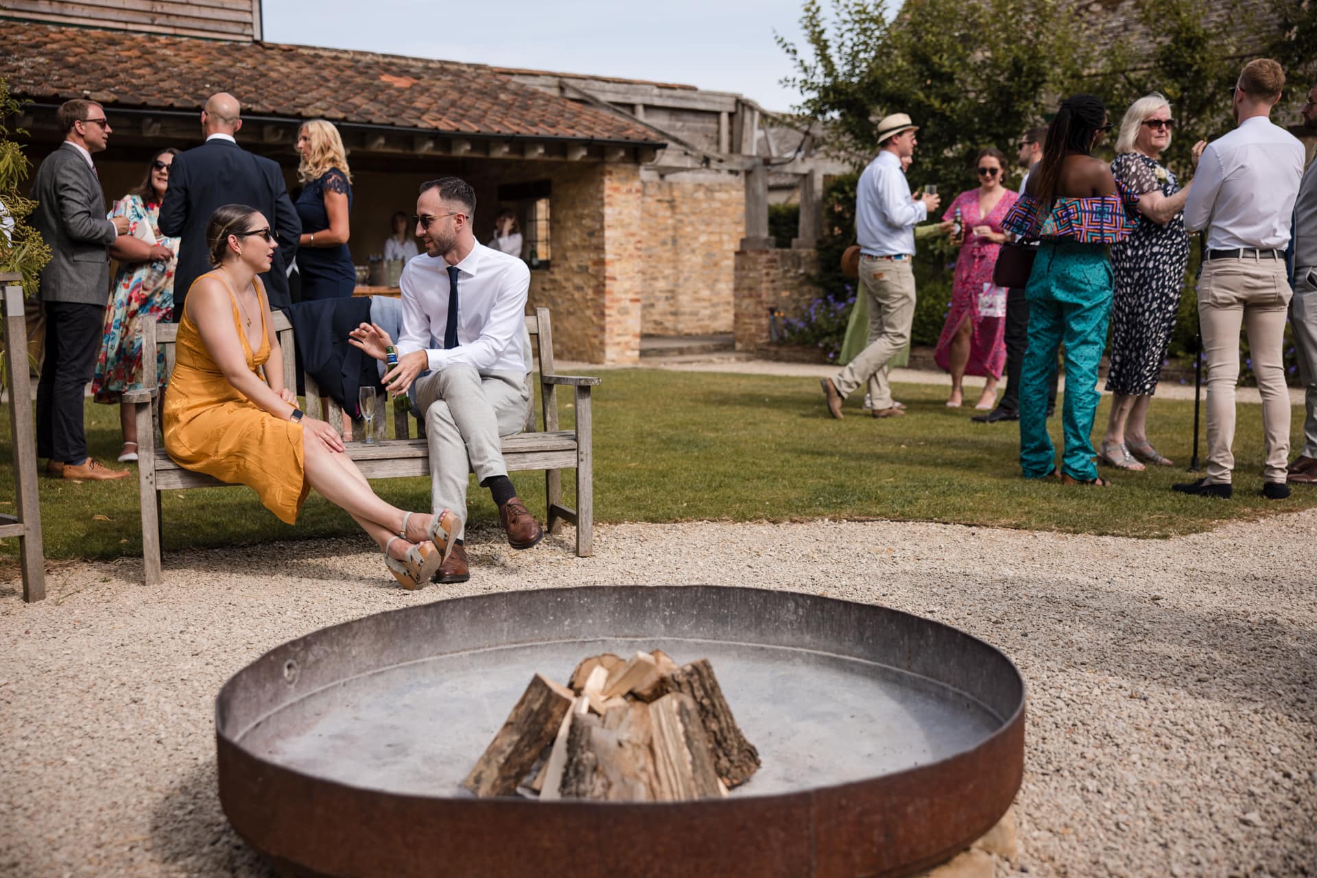 Guests in the courtyard with fire pit in the foreground at Oxleaze Barn