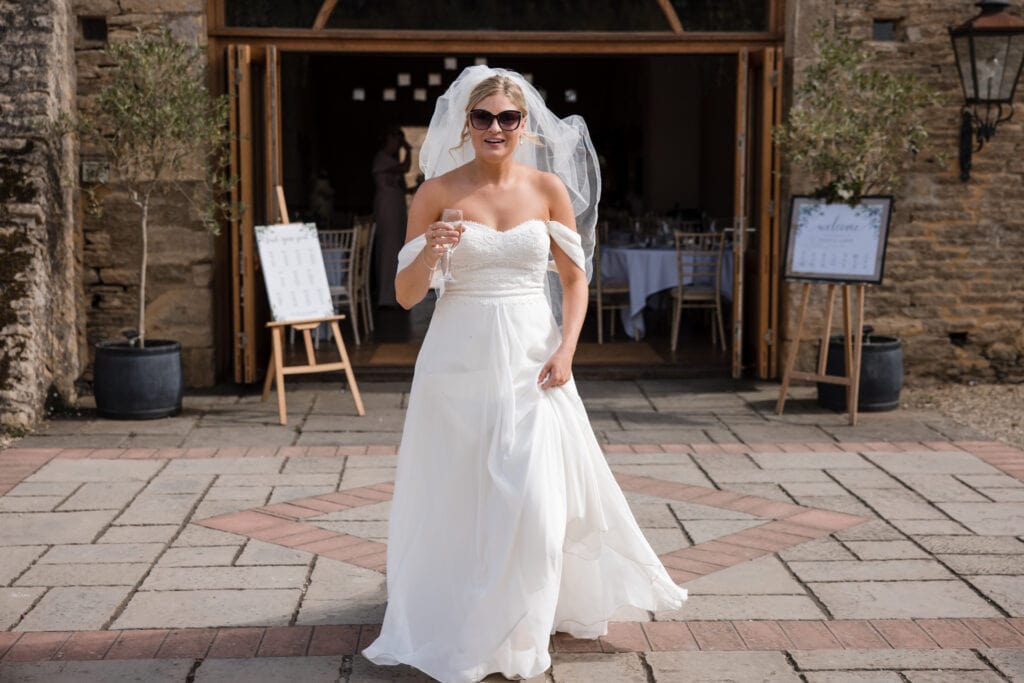 Bride walking into courtyard at Oxleaze Barn