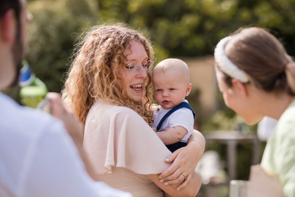 Bridesmaid holding her baby close to chest at Oxleaze Barn