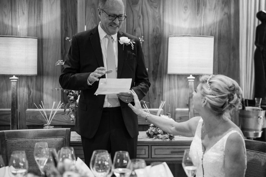 Emotional groom speech at Le Manoir with bride reaching out.