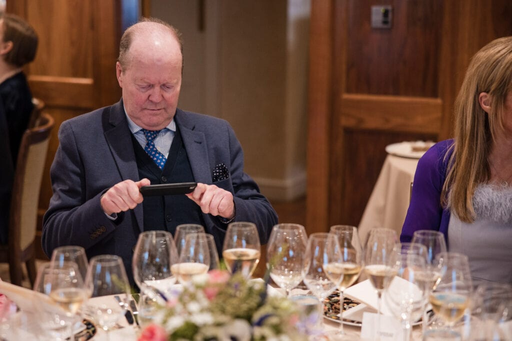 A guest using his mobile to see the menu at Le Manoir