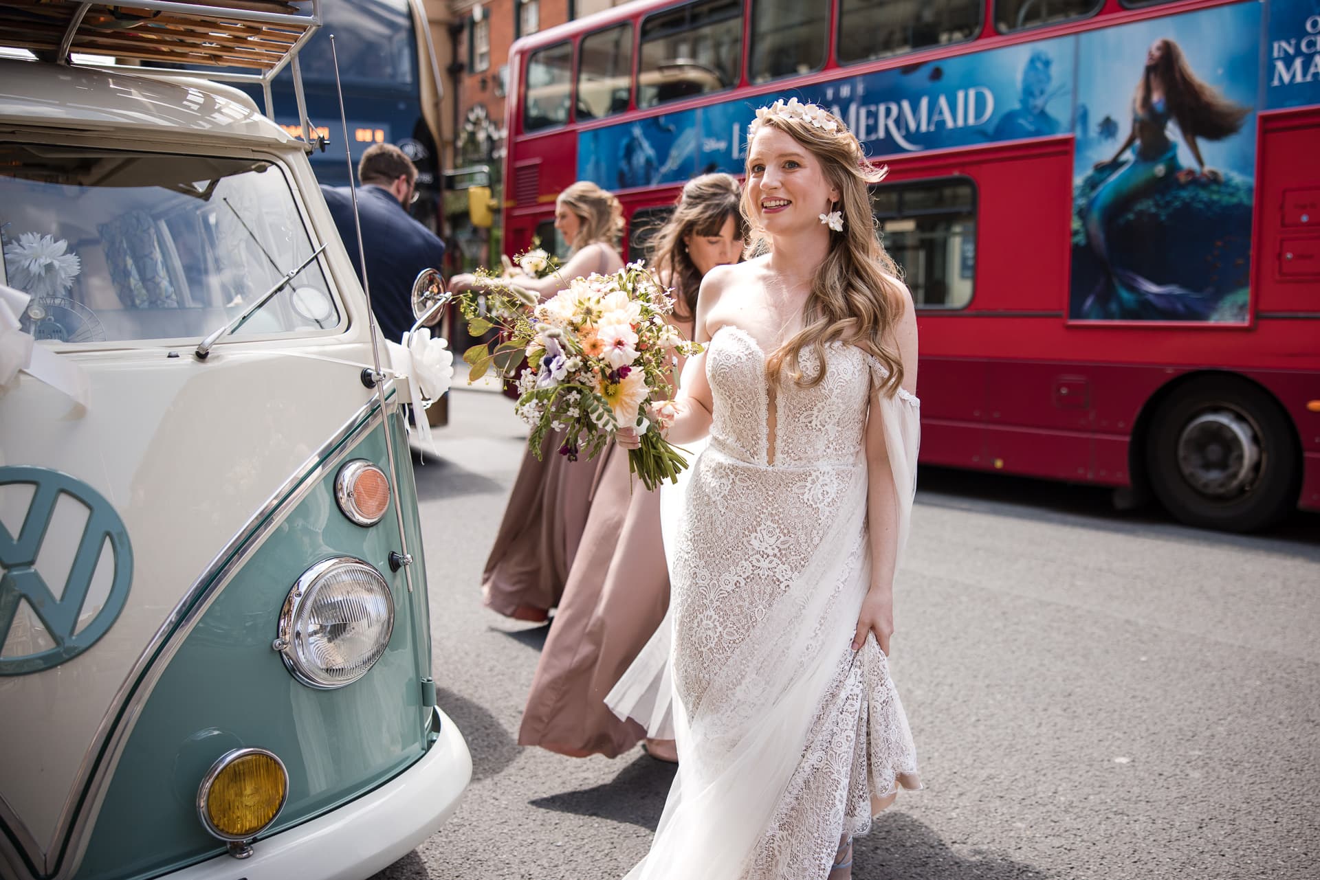 Bride walking next to the Campervan with a Double Decker in the background