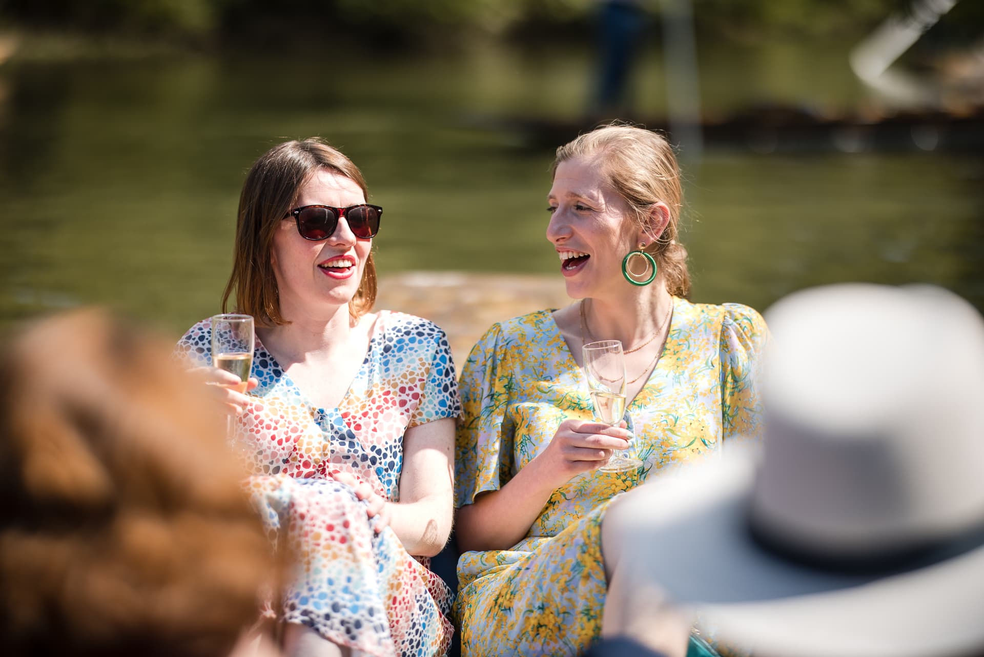 Two wedding guests drinking Champagne sat on the Punt at the Cherwell Boathouse