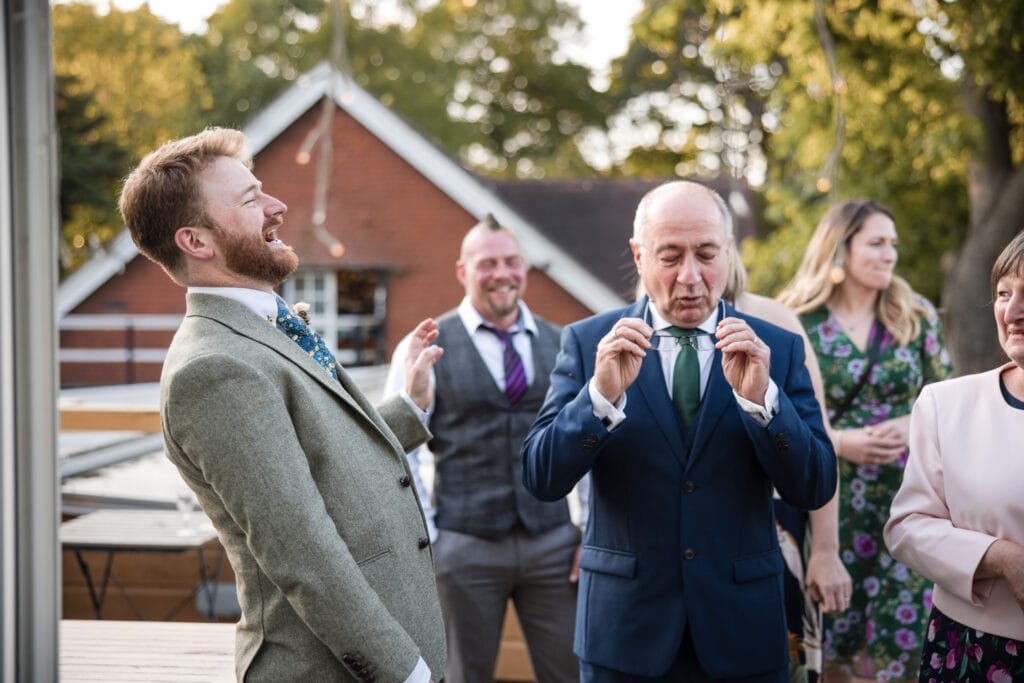 Groom laughing with his father at the Cherwell Boathouse