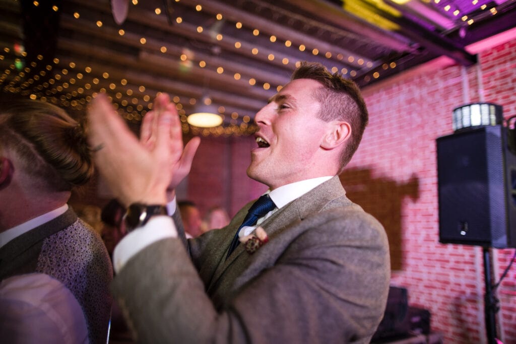 Groomsman clapping whilst on the dancefloor at the Cherwell Boathouse.