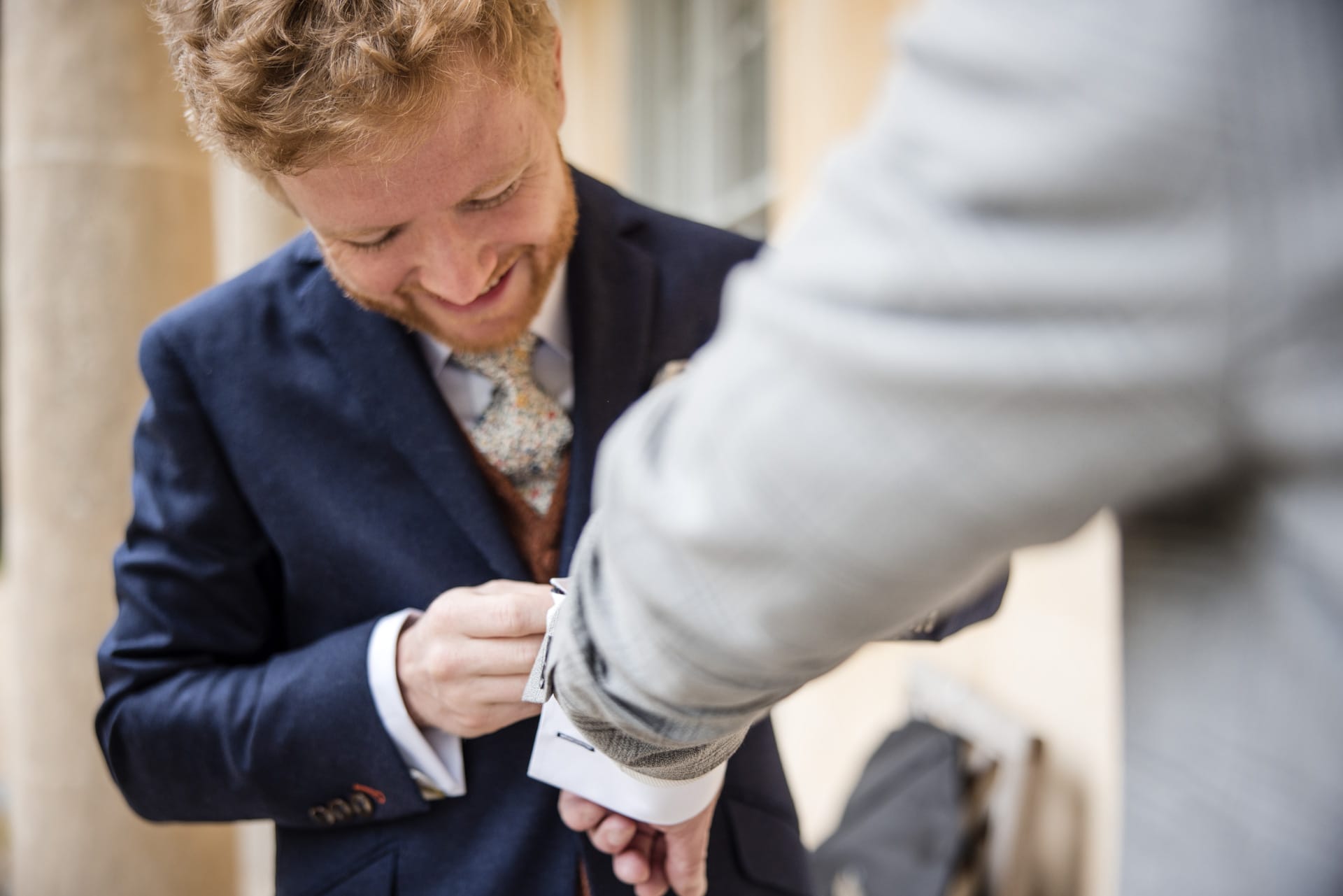 Groom helping family guest get ready for wedding day