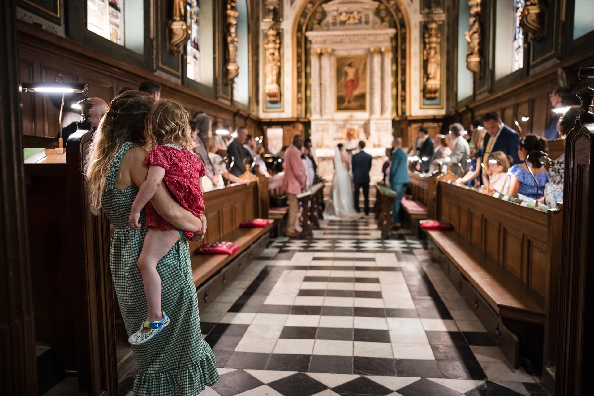 A mother and young child look on at the wedding in the Damon Wells Chapel at Pembroke College