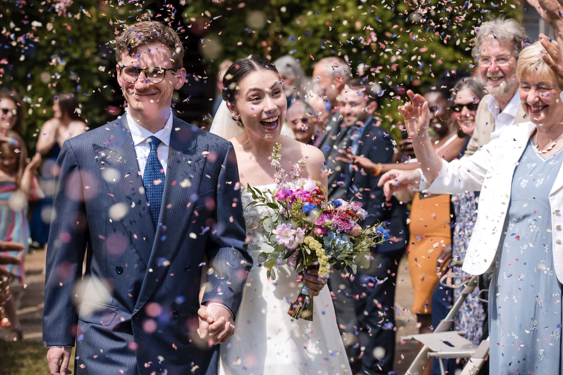 Confetti covering the bride and groom during a Pembroke College wedding