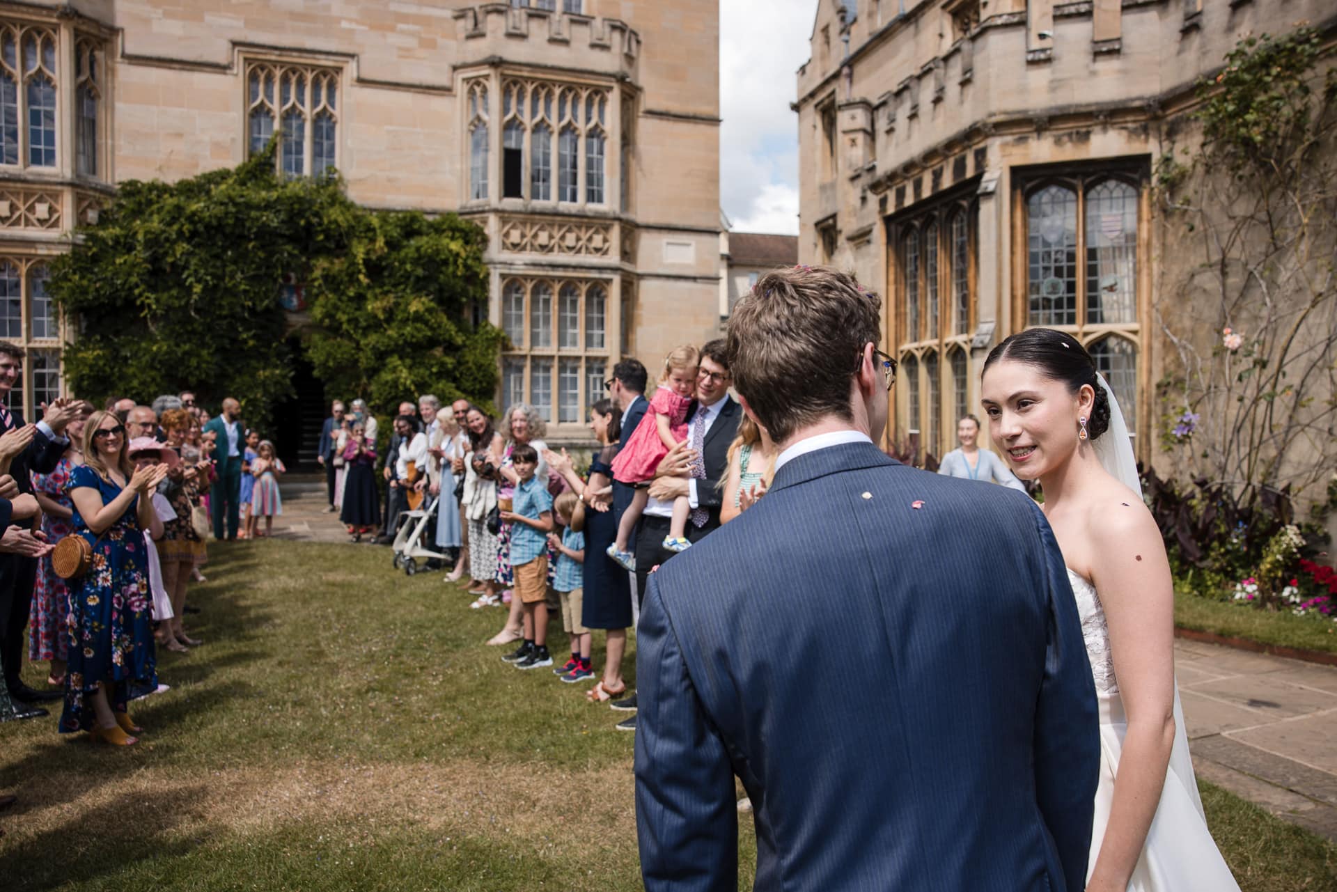 The Bride and Groom looking at each other, whilst the guests are still standing in the confetti line up, within the grounds of Pembroke House