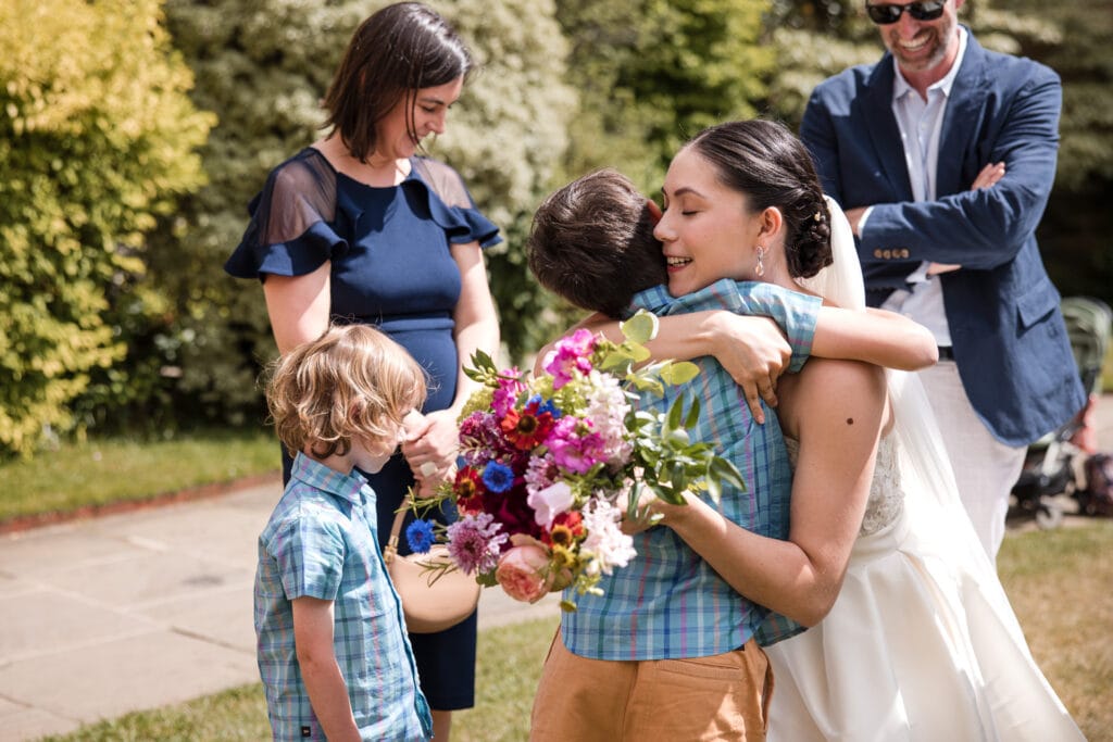 The bride giving a young lad a big hug in the grounds of Pembroke College.