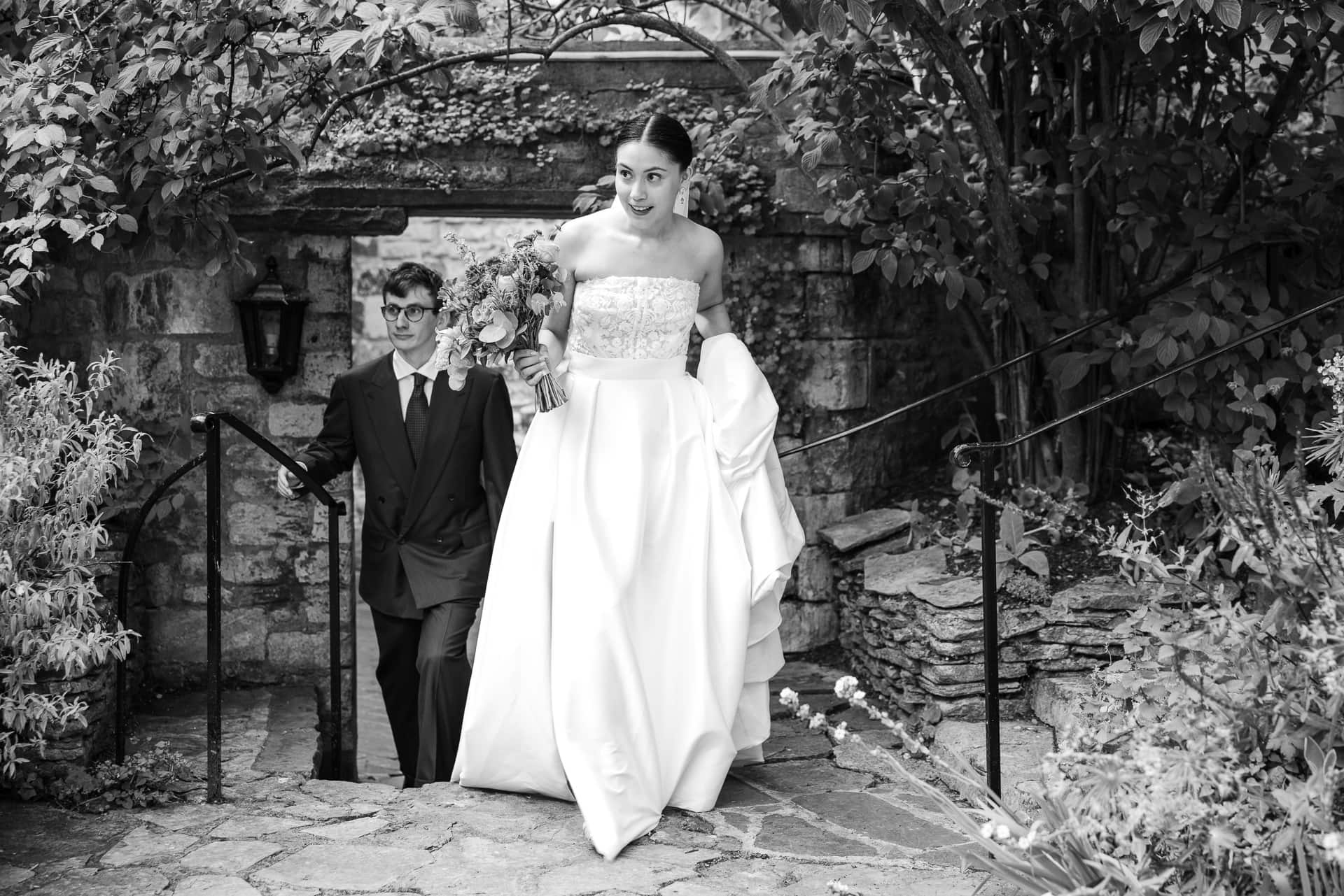 The Bride and Groom walking up the steps looking at the guests at the Master’s Garden at Pembroke College
