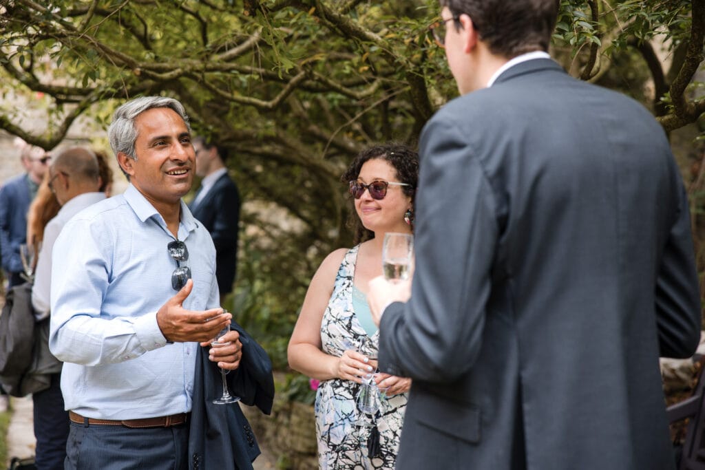 Wedding Guests enjoying champagne in the Masters Garden at Pembroke College.