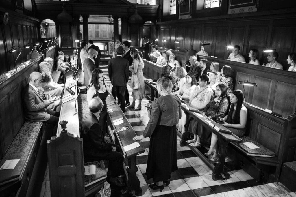 Guests standing and seating chatting inside the Damon Wells Chapel at Pembroke College