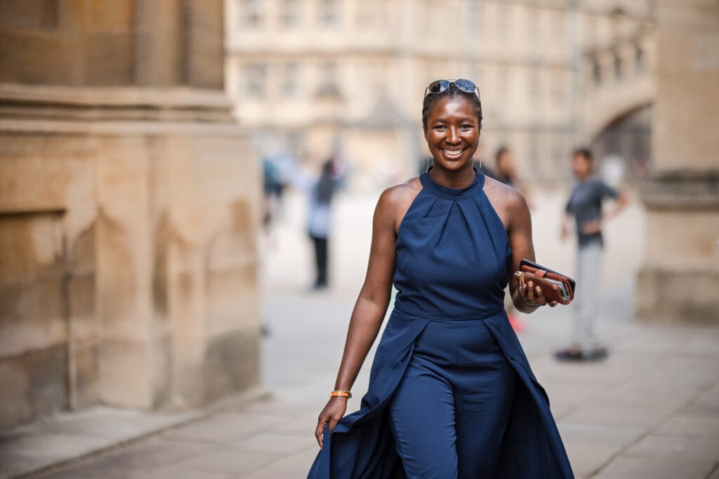 Wedding guest walking and smiling outside of the Sheldonian Theatre