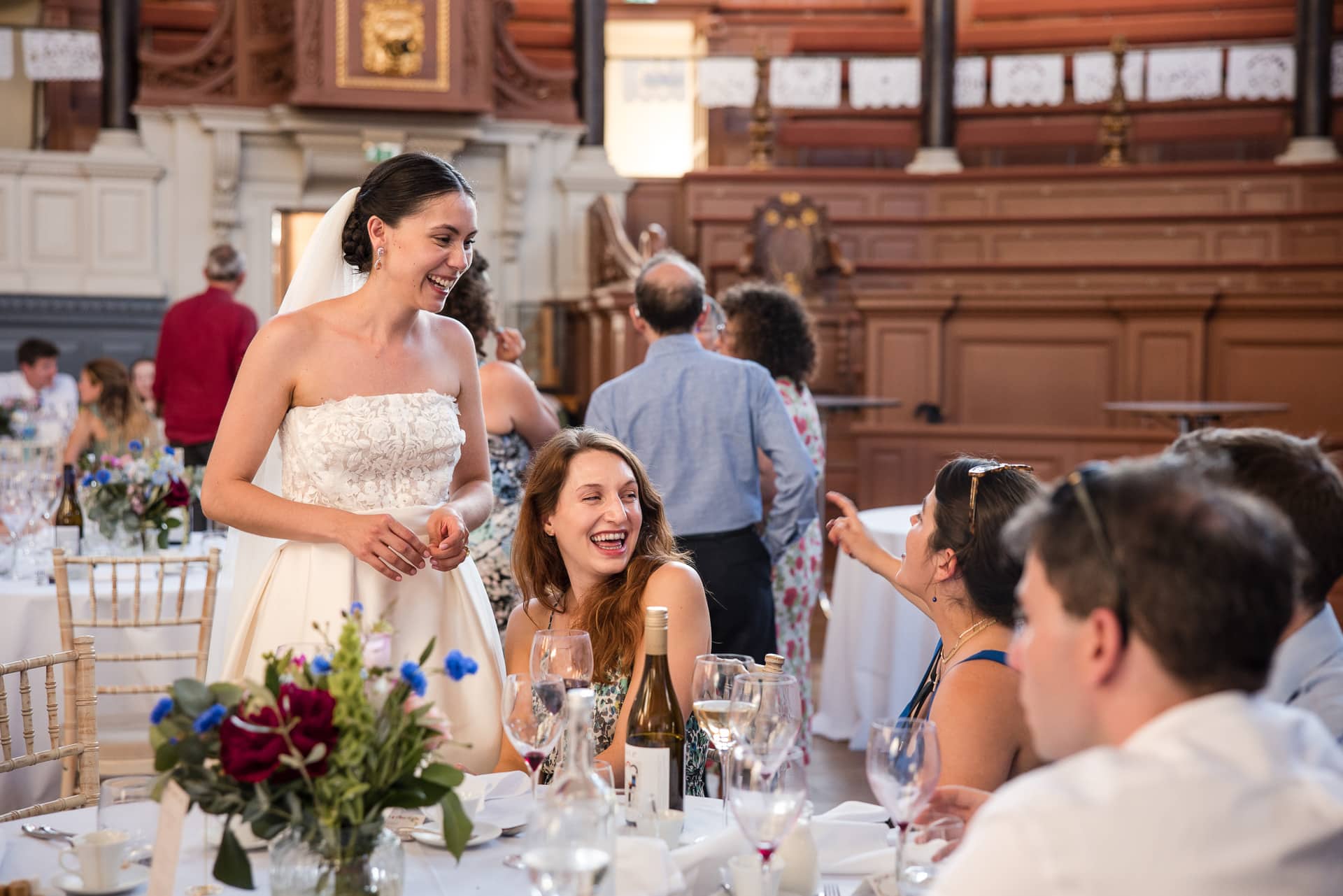 Bride and her friends laughing at the dining table inside the Sheldonian Theatre