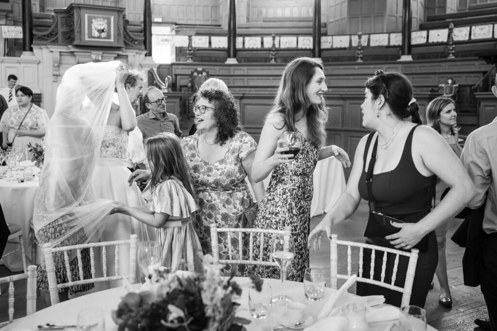 The bride being wrapped up in her veil by young guests at the Sheldonian Theatre
