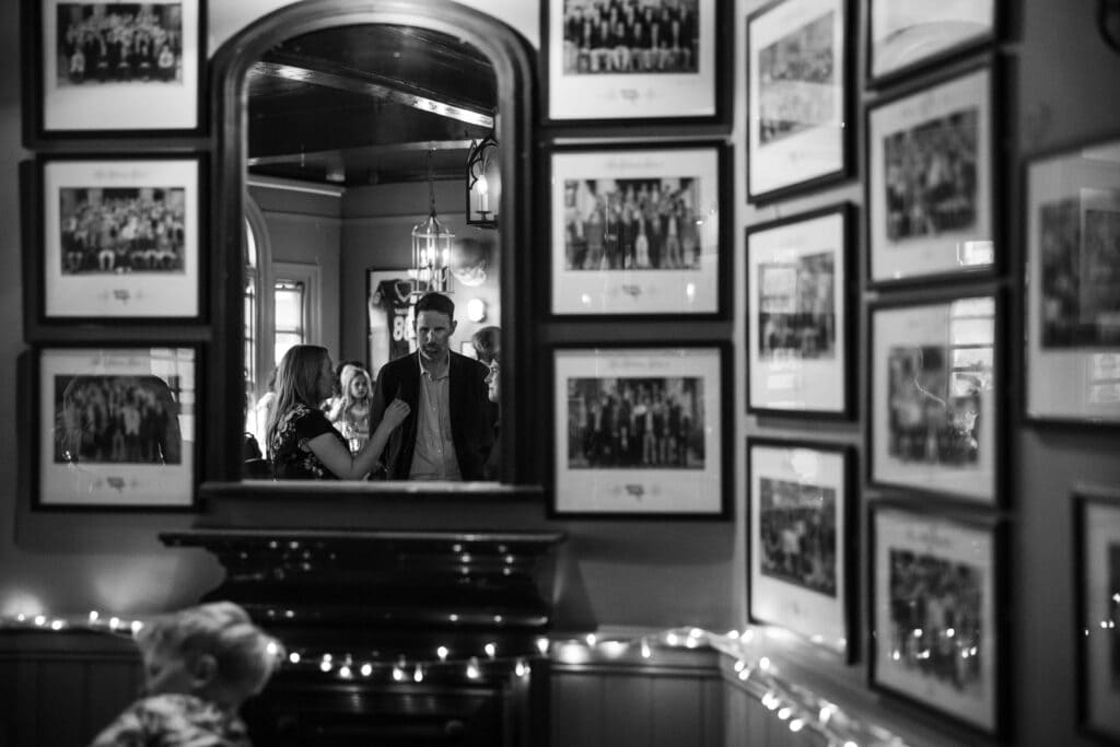 Oxford College photos on the walls with guests reflected in the mirror at St Aldates Tavern