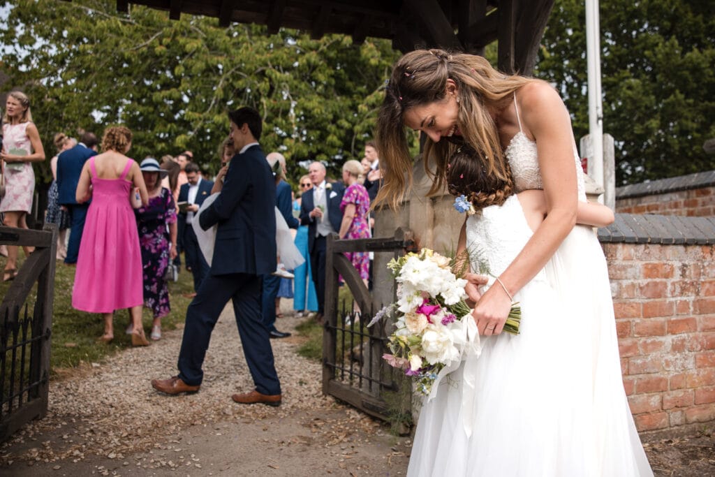 Bride and pagegirl cuddle after the wedding ceremony at the Sandhurst Wedding