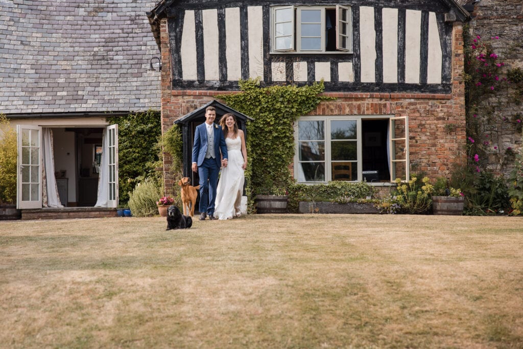 Bride and Groom walking from the old Farm House with the dogs at the Sandhurst Farm Wedding Reception