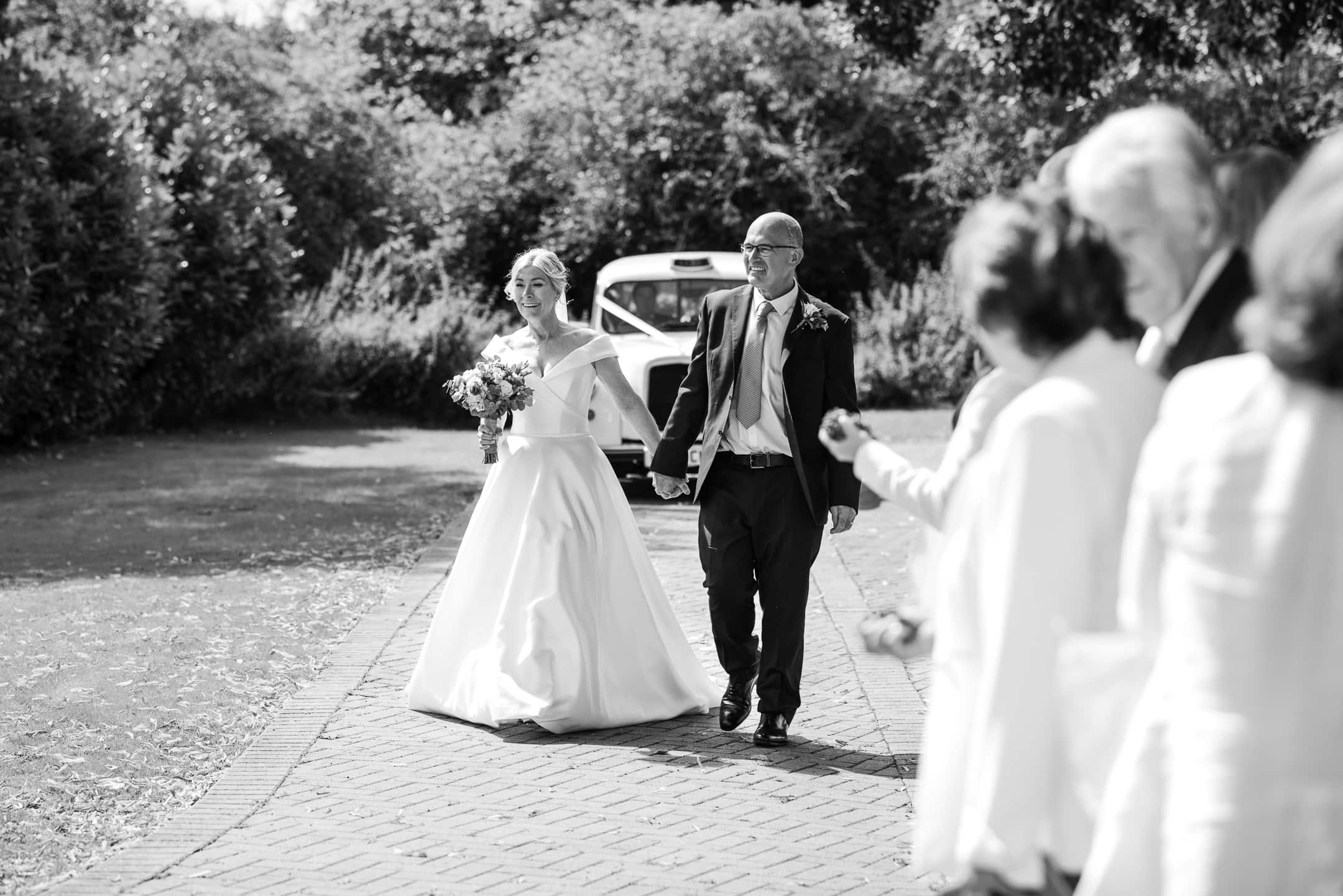 Bride and Groom arrive by white London cab at Dovecote Barn Wedding