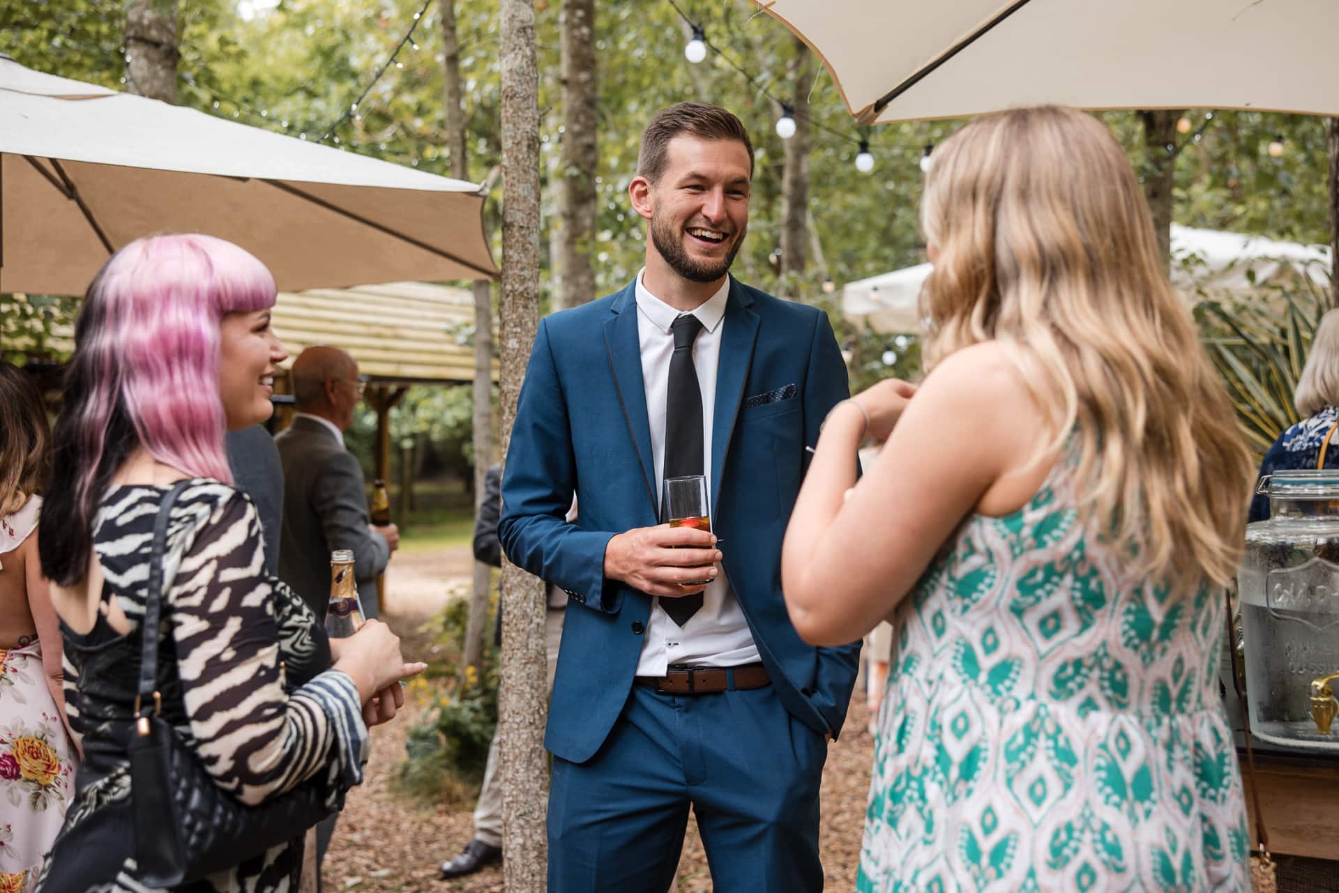 Guests laughing and drinking amongst the tree's at the Endeavour Woodland wedding venue
