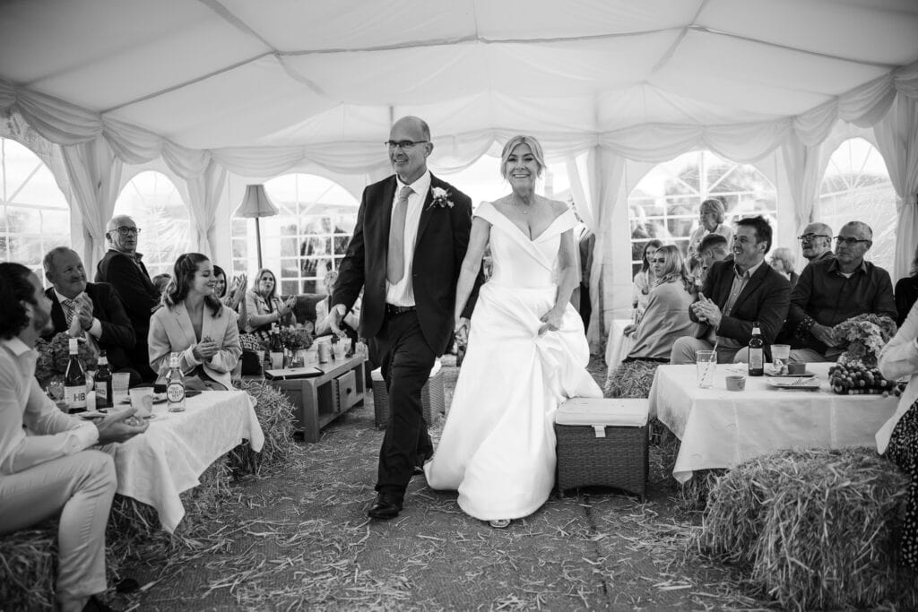 Bride and Groom walking towards the dance floor in the marque for the first dance.