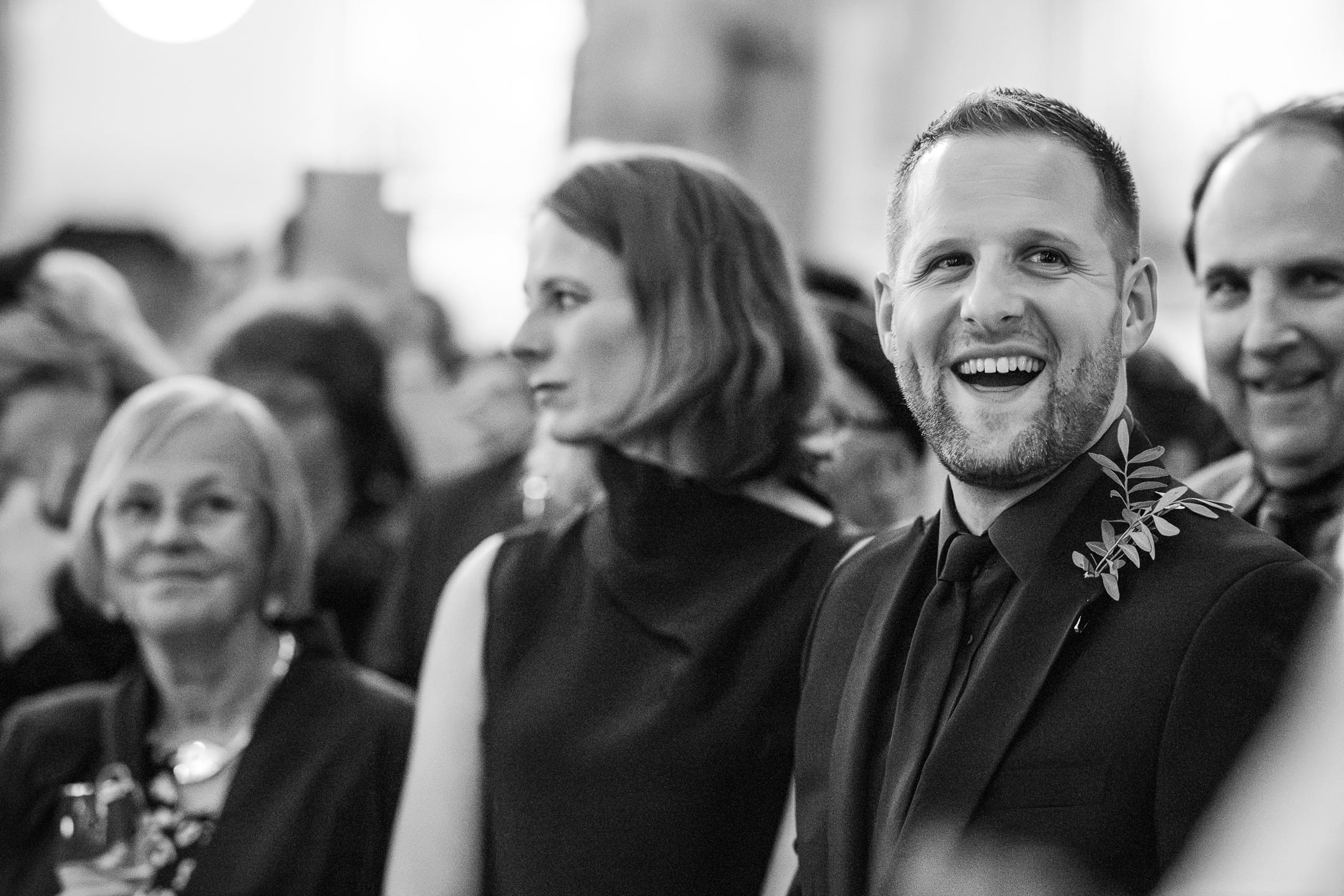 Guests laughing during speeches at the Oxford Natural History Museum wedding reception.