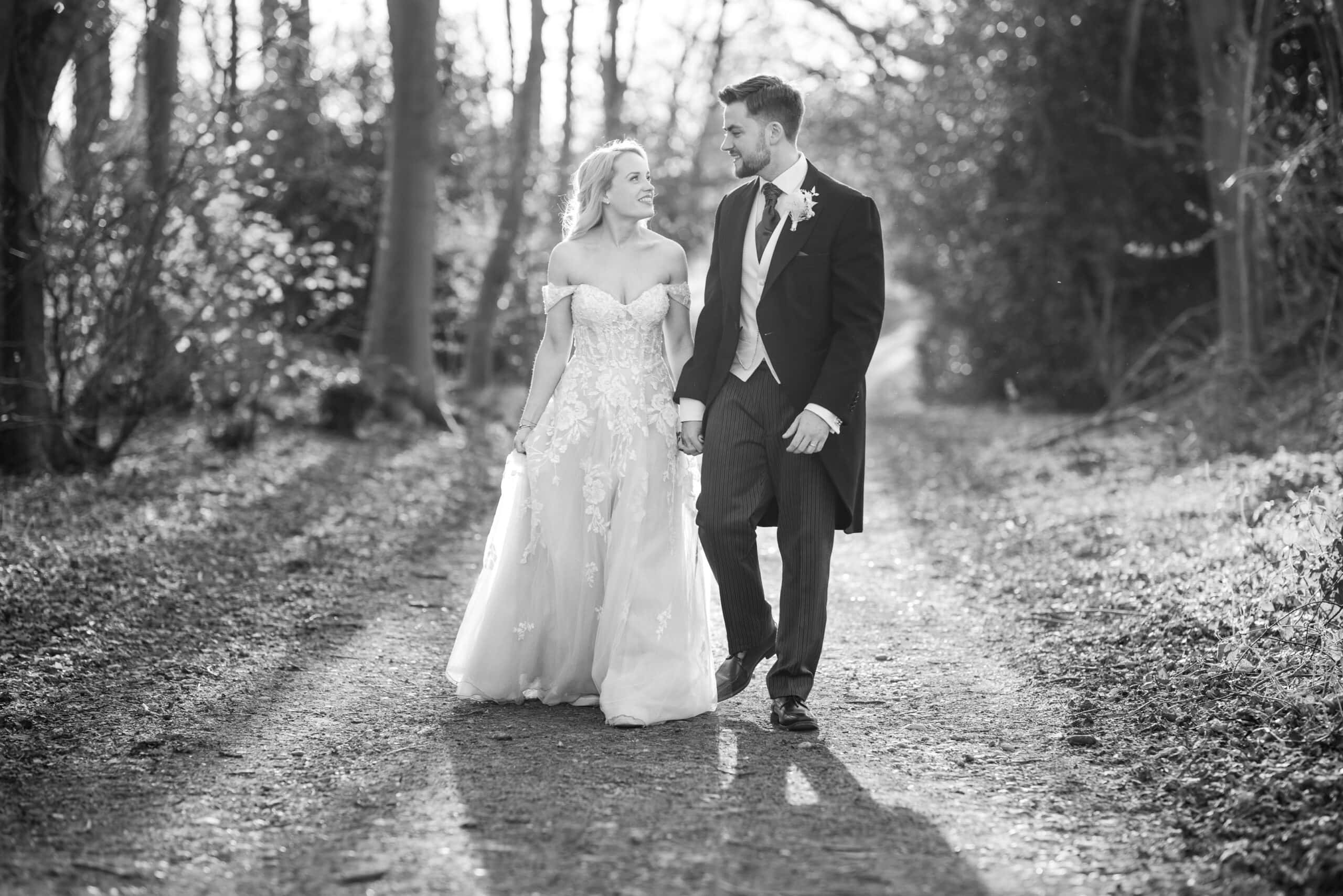 Bride and Groom walking down wooded lane at Chenies Manor