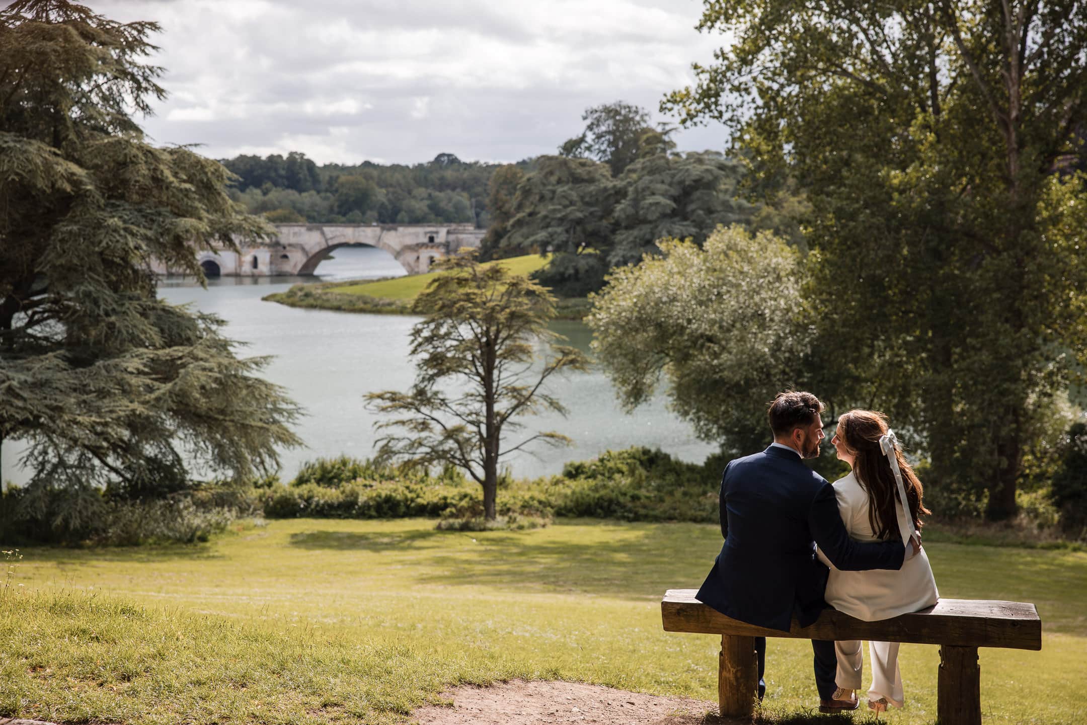 Bride and Groom sitting on a bench with beautiful views across the Blenheim Palace estate.
