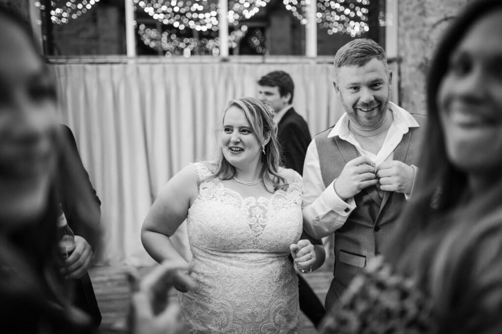 Bride dancing with guest undoing his shirt buttons