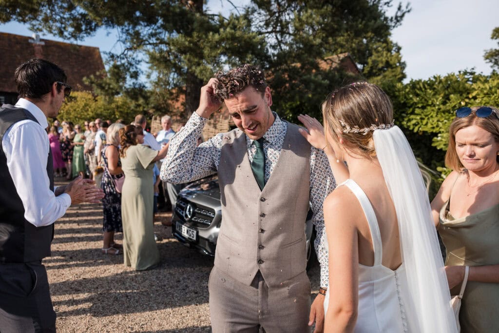 Bride and Groom stop to clear the confetti off themselves